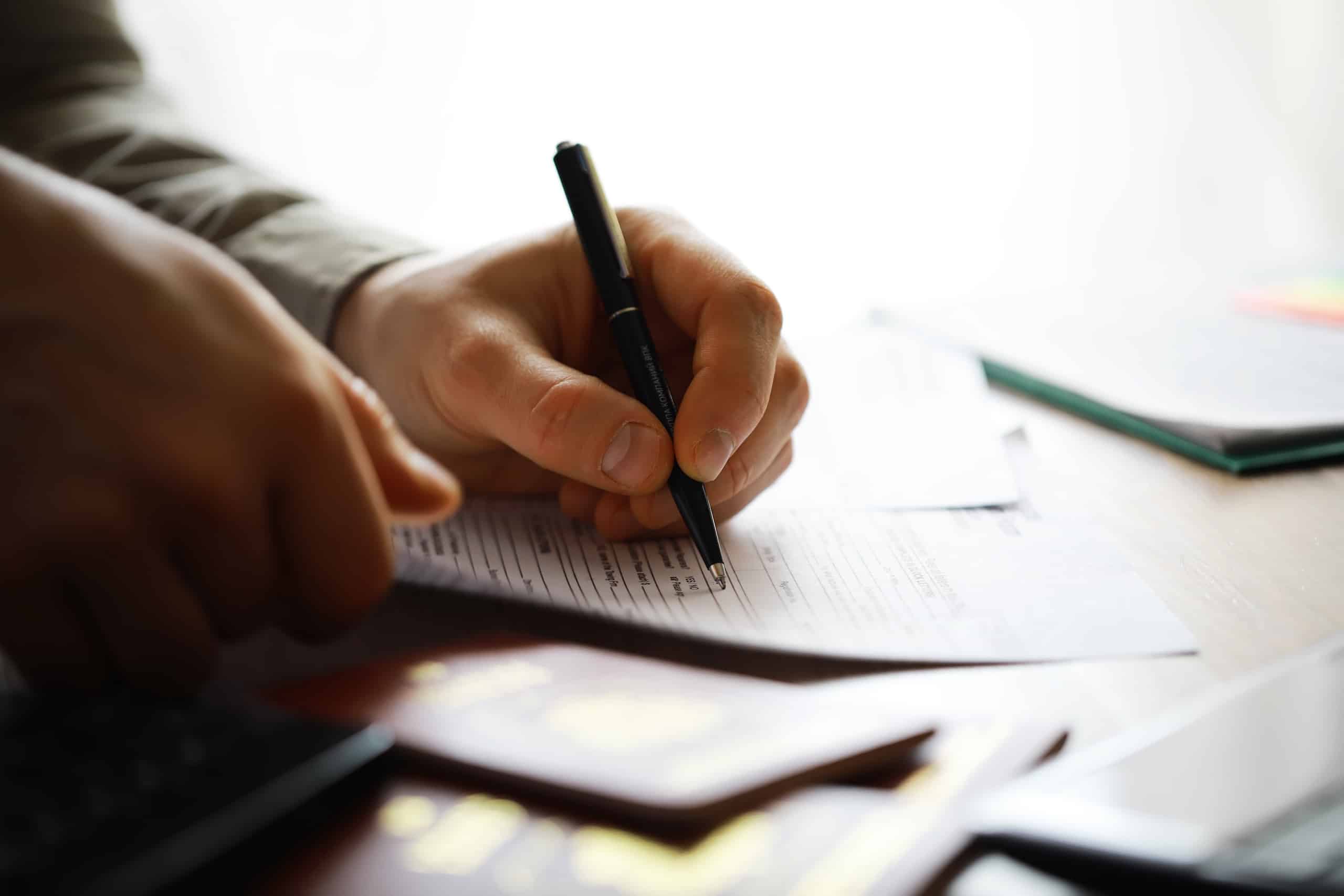 Close-up of Hands Filling Out Documents with Pen for Business or Personal Use